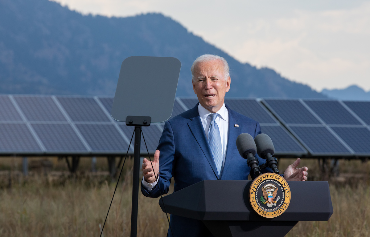 joe biden speaks in front of solar panel array